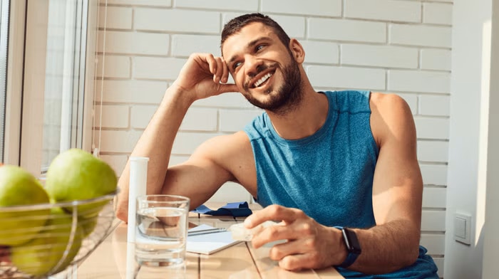 healthy man smiling at table with fruit and water